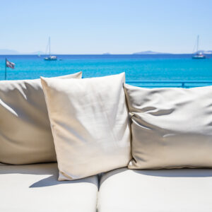 24 inch patio throw pillows sitting on outdoor furniture with ocean in the background