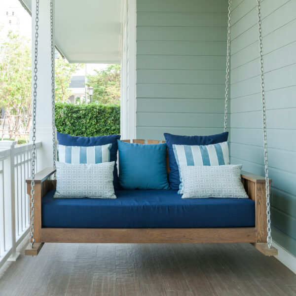 Covered outdoor sofa swing with blue cushions in garden