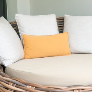 Patio lumbar pillow sitting on a wicker patio bed