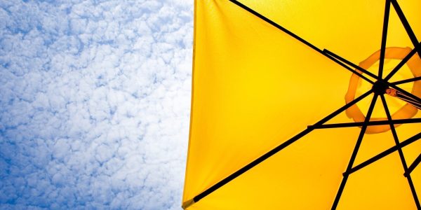 Yellow sun umbrella on a blue sky. Summer background.